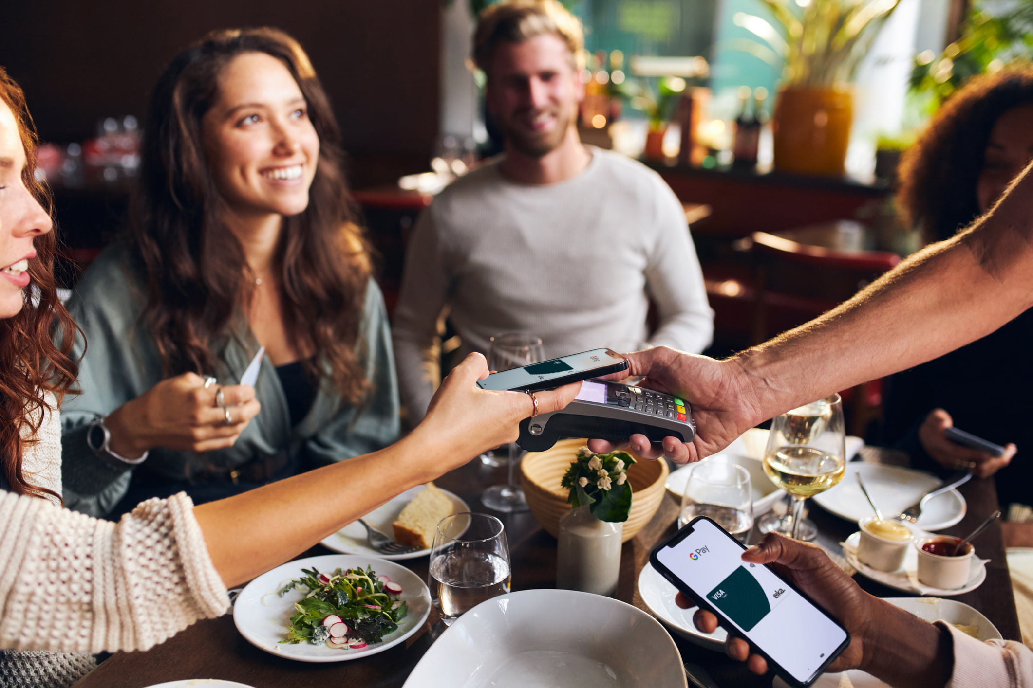 Dame betaler med mobilen på restaturant.