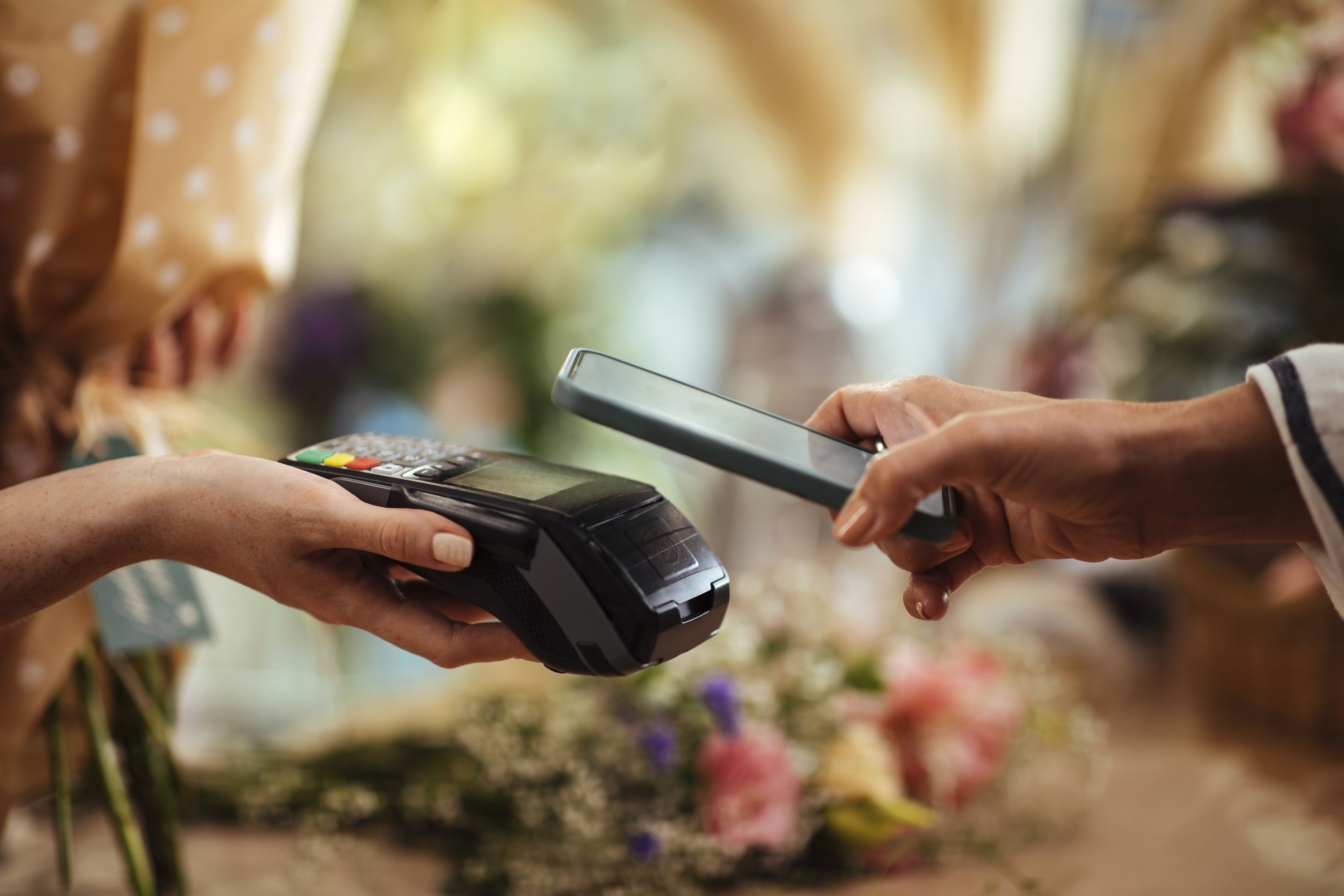 Kunde betaler kontaktløst med mobilen i blomsterbutikk.