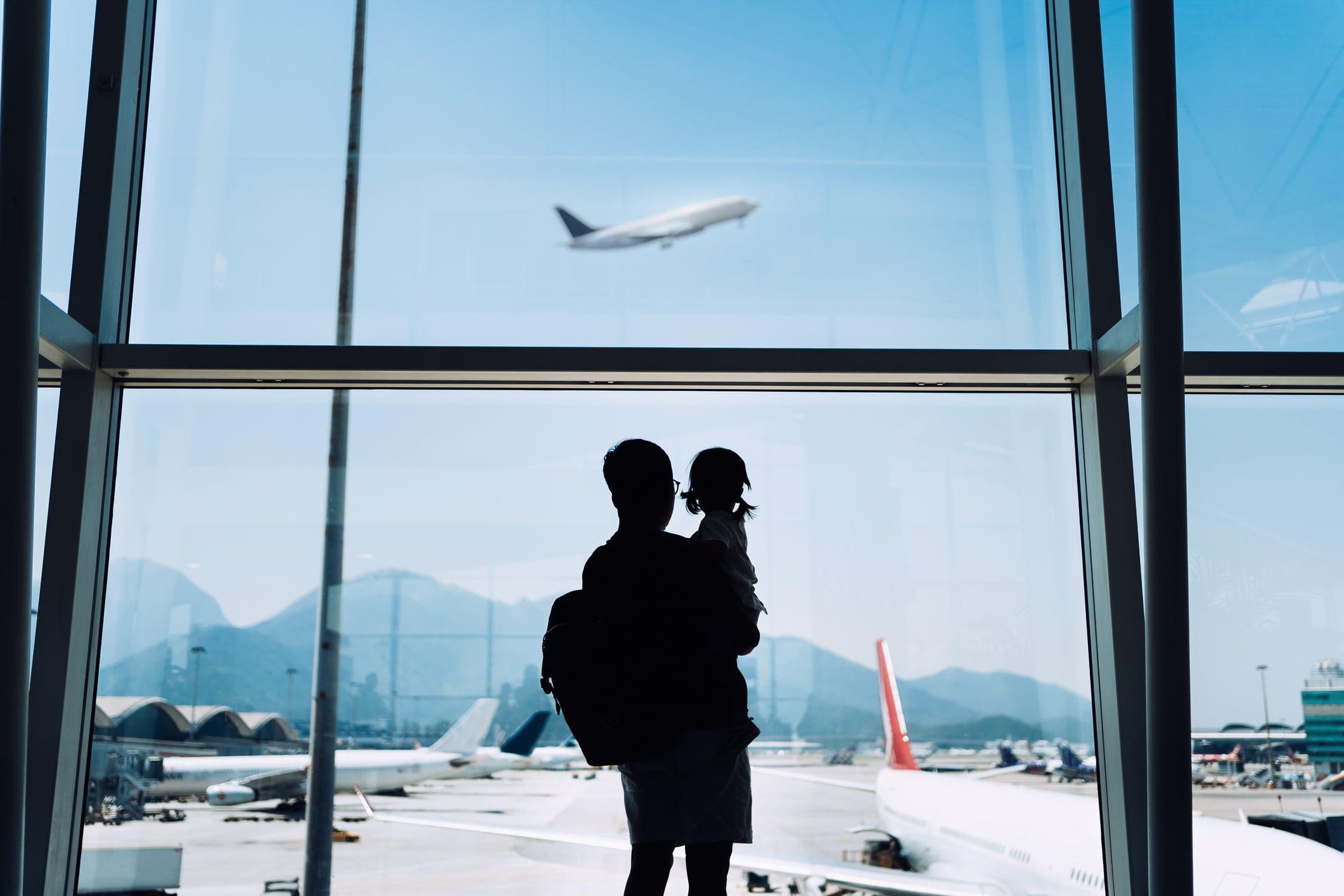 Far og datter ser på fly på flyplass