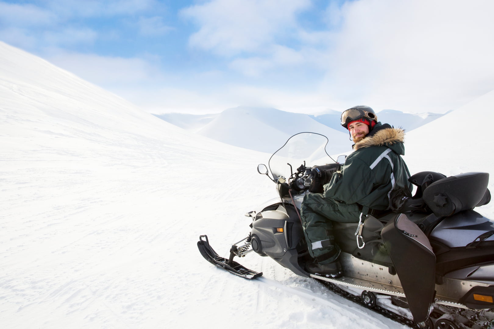 Mann på svart snøscooter i snødekket område