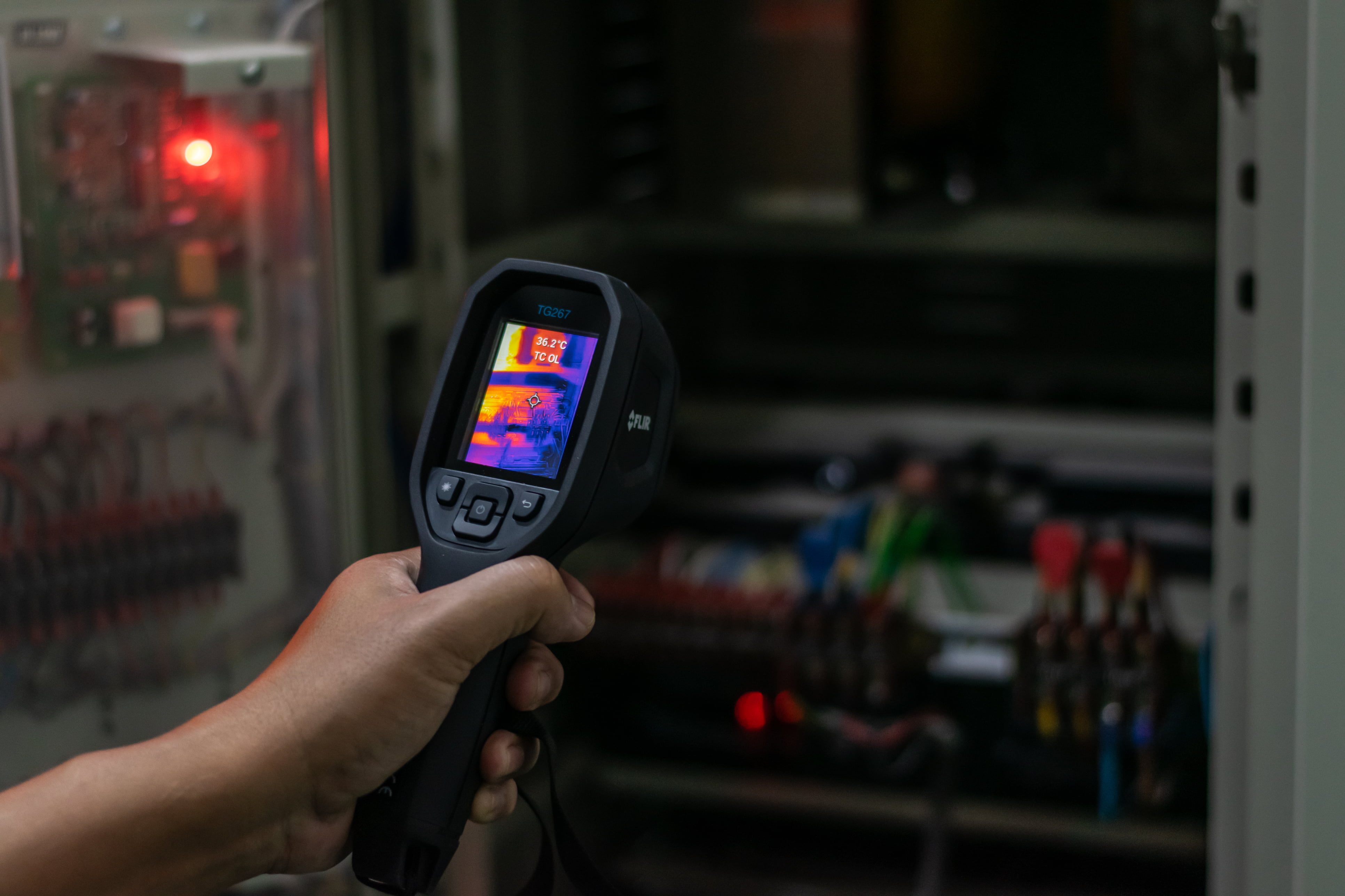 Elektriker som bruker et varmesøkende kamera for å finne varme punkter i et el-anlegg