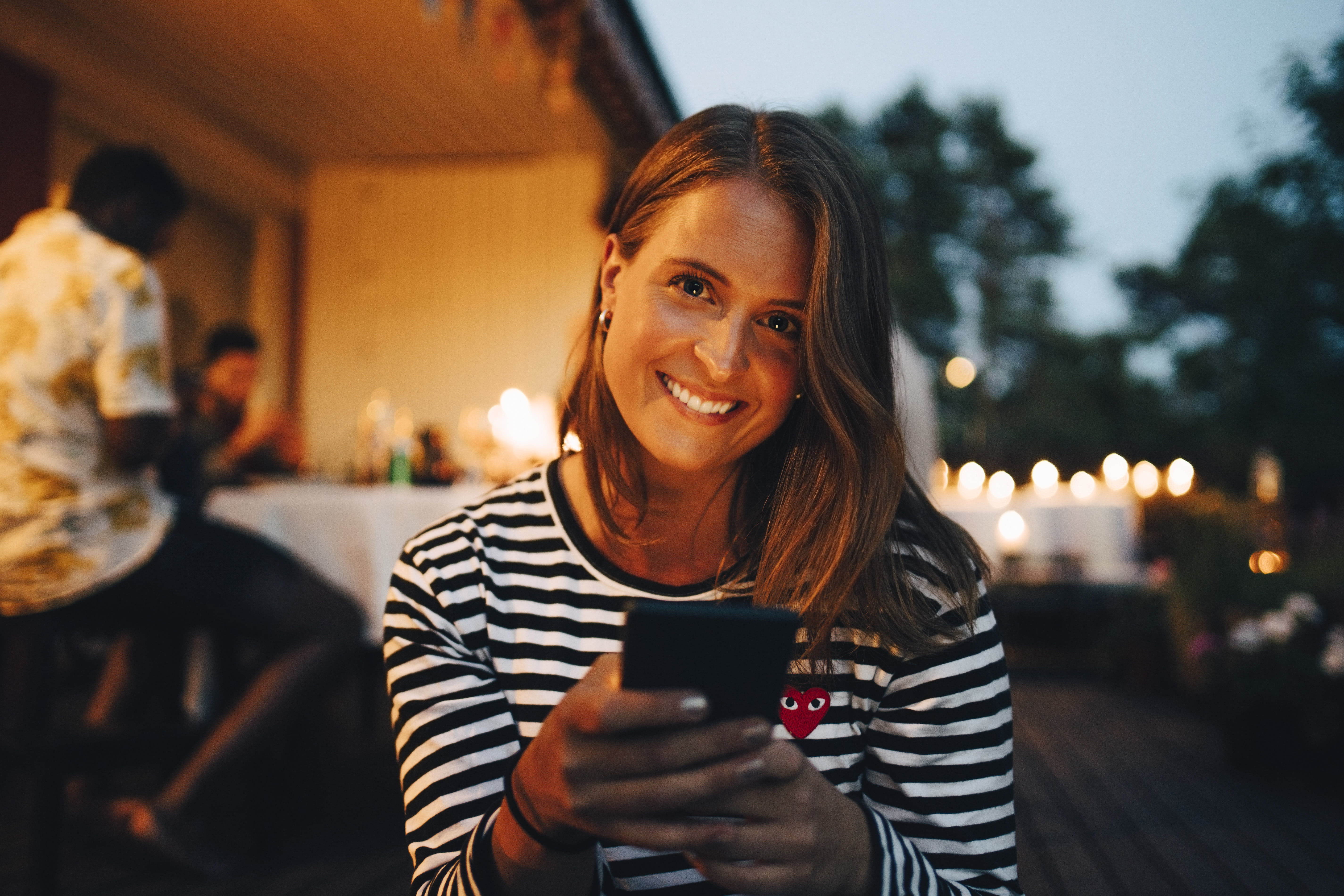 Dame med mobil smiler til kamera