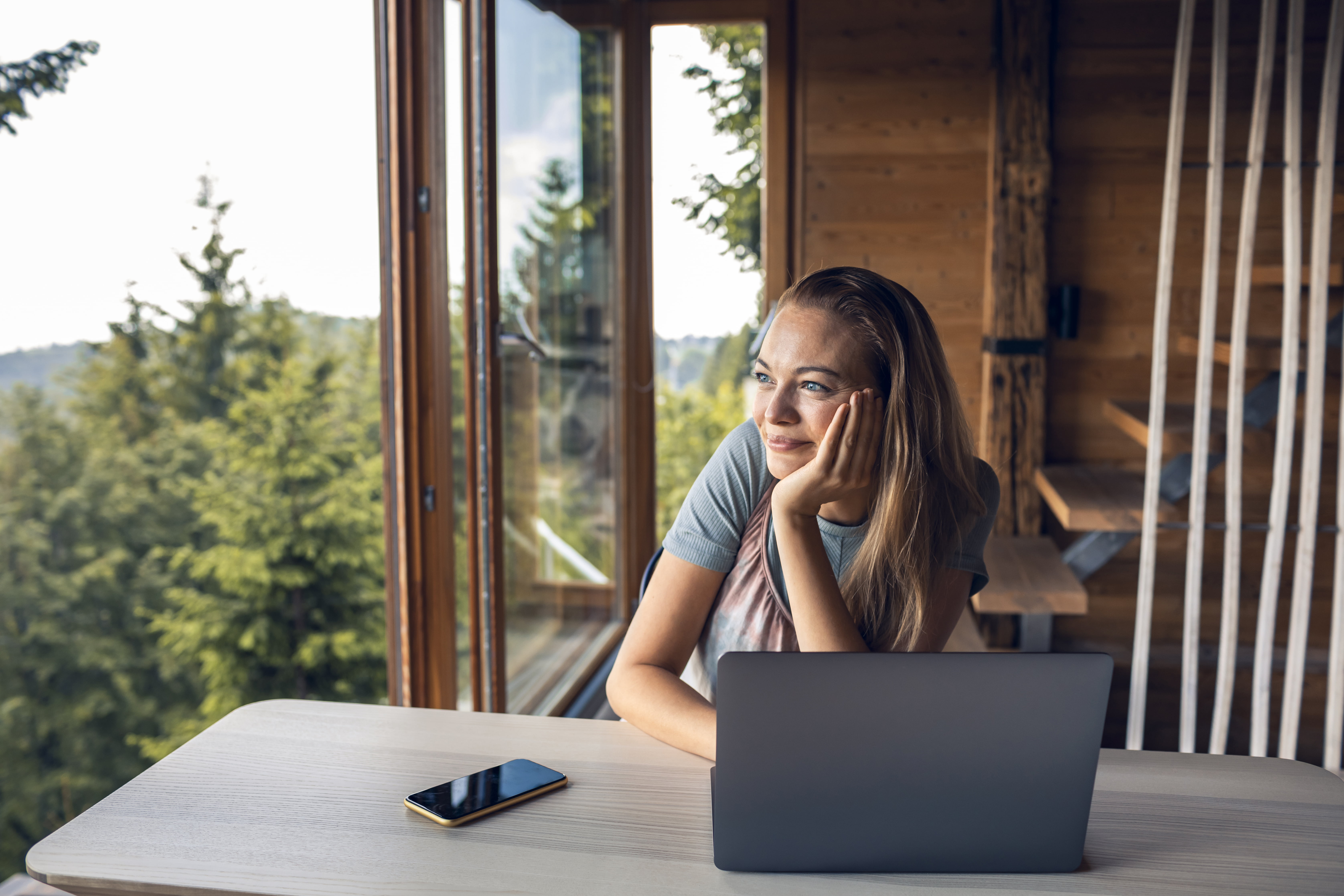 Close up of a mid adult woman working on a laptop from her cabin in the woods