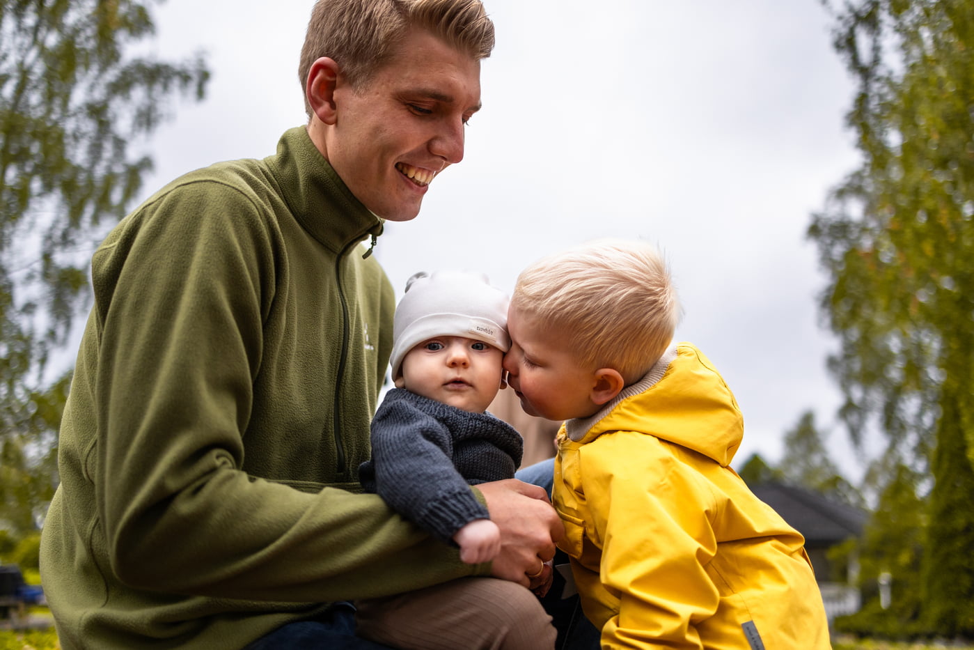 far med lillebror på fanget sitt og storebror gir han en klem