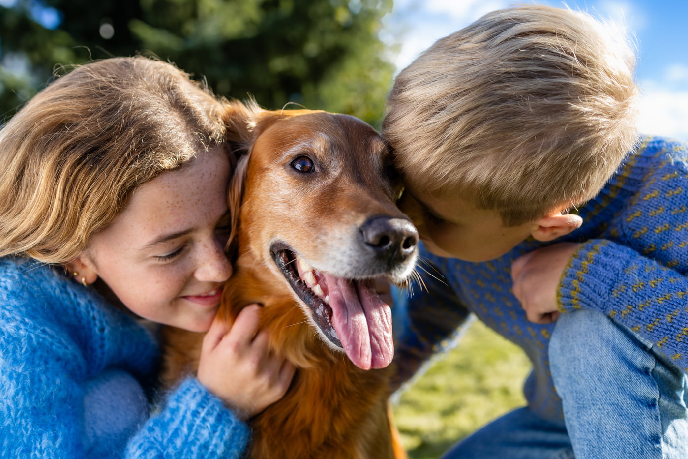 Jente og gutt koser hund mellom seg