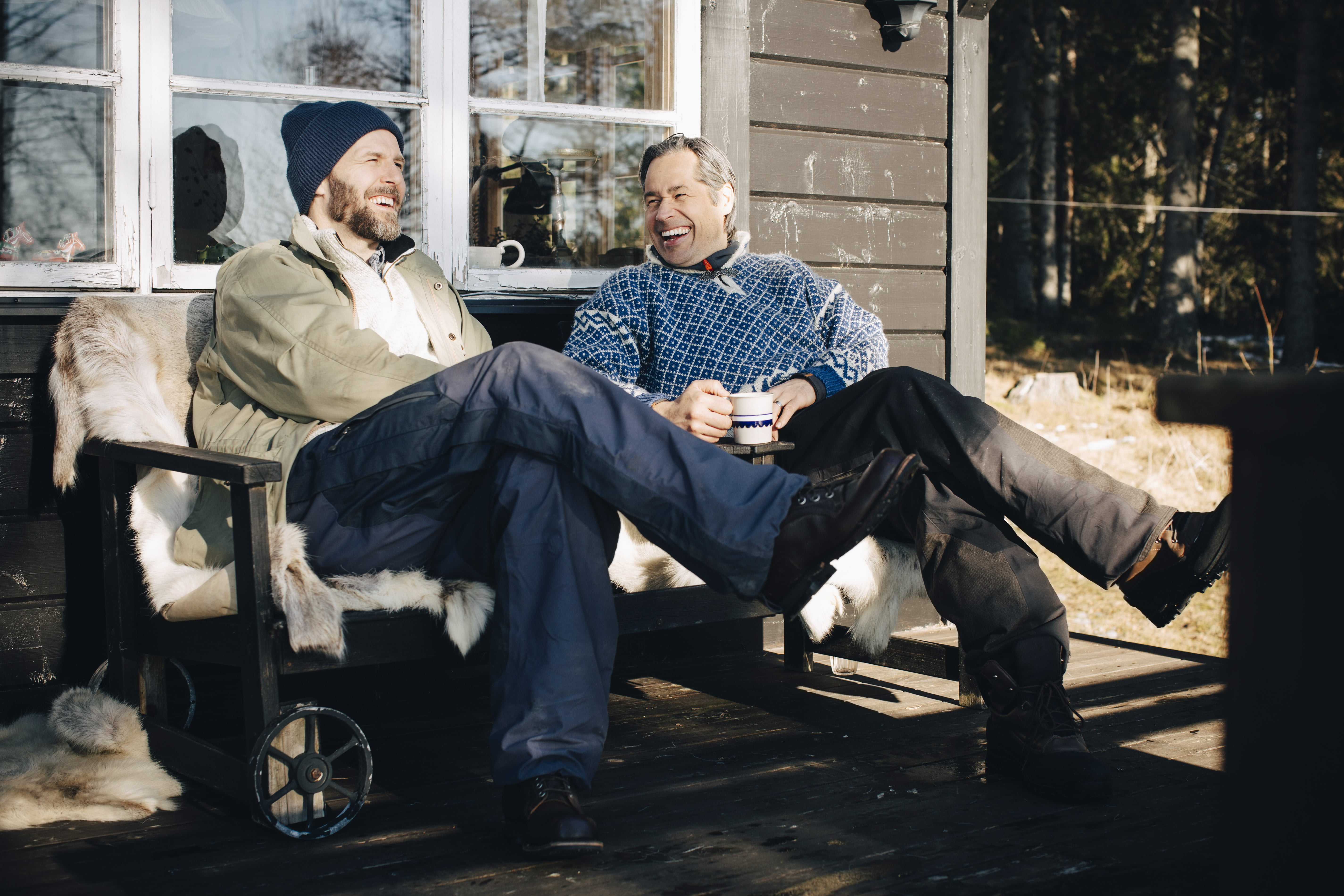 To blide menn som sitter på verandaen og drikker kaffe